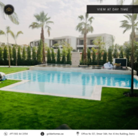 Daytime view of luxury pool surrounded by grass and palm trees in Dubai residential area.