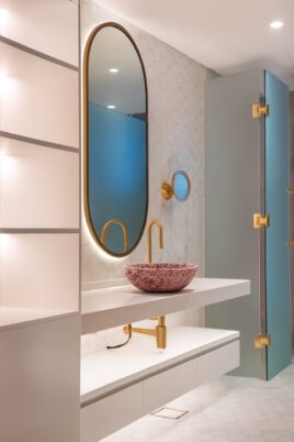 Modern luxury bathroom with gold accents, pink stone sink, and geometric tile design in high-definition portrait format.