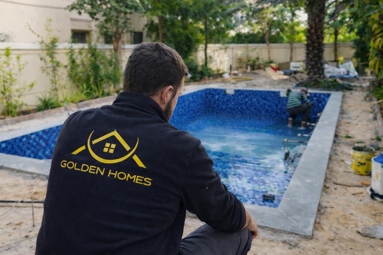 Golden Homes professional labour inspecting swimming pool construction project with blue mosaic tiling and premium finishing