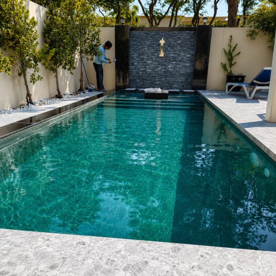 Swimming pool construction in Dubai with water feature wall, landscaping, and professional inspection